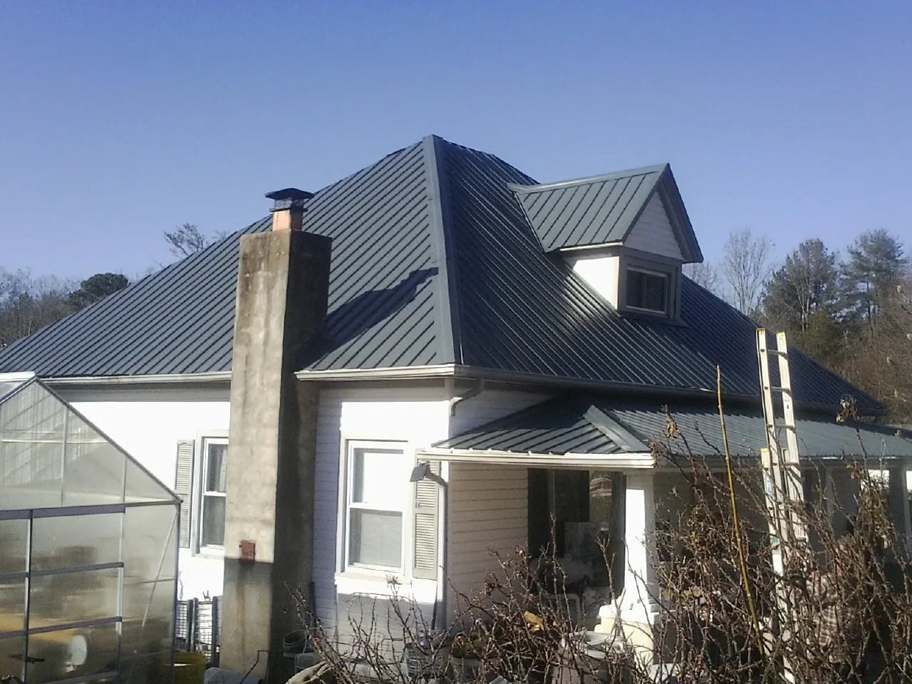 Dark blue standing seam metal roof on a white farmhouse with dormer — Slate & Tile Roof Repair by Roofing Brothers in Laketon