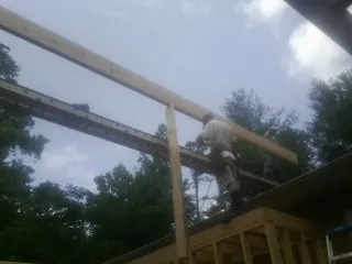 Carpenter setting a ridge beam over a new addition frame — Ice Dam Removal by Roofing Brothers in Laketon