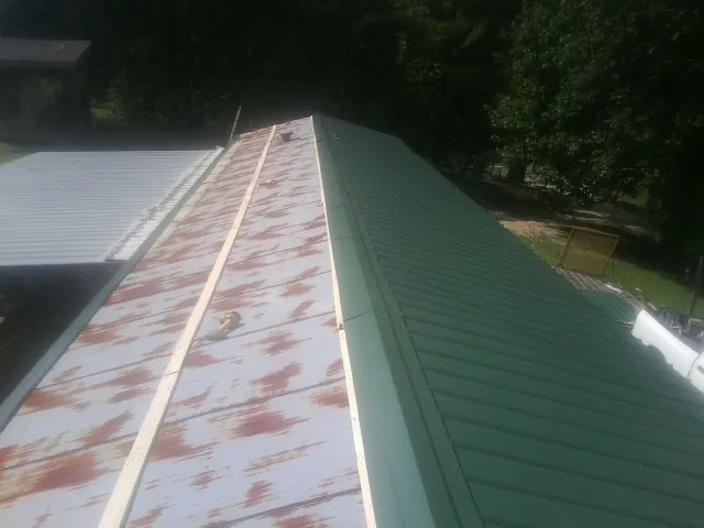 Old rusted panels beside newly installed green metal roofing — Wind Damage Roof Repair by Roofing Brothers in Laketon