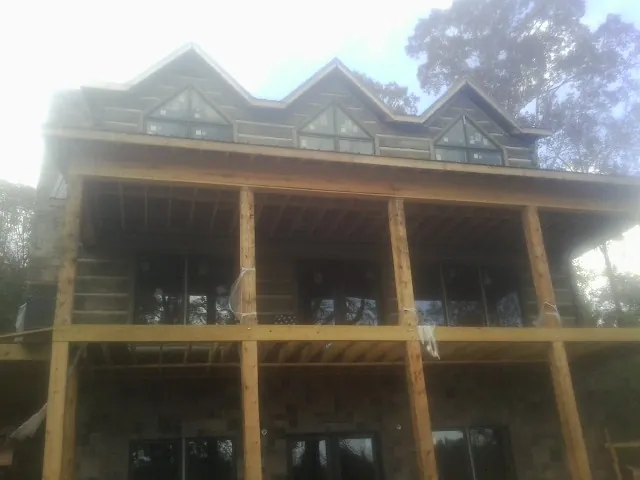 Dormers and porch framing on a large log home under construction — Roof Coating work by our crew in Laketon