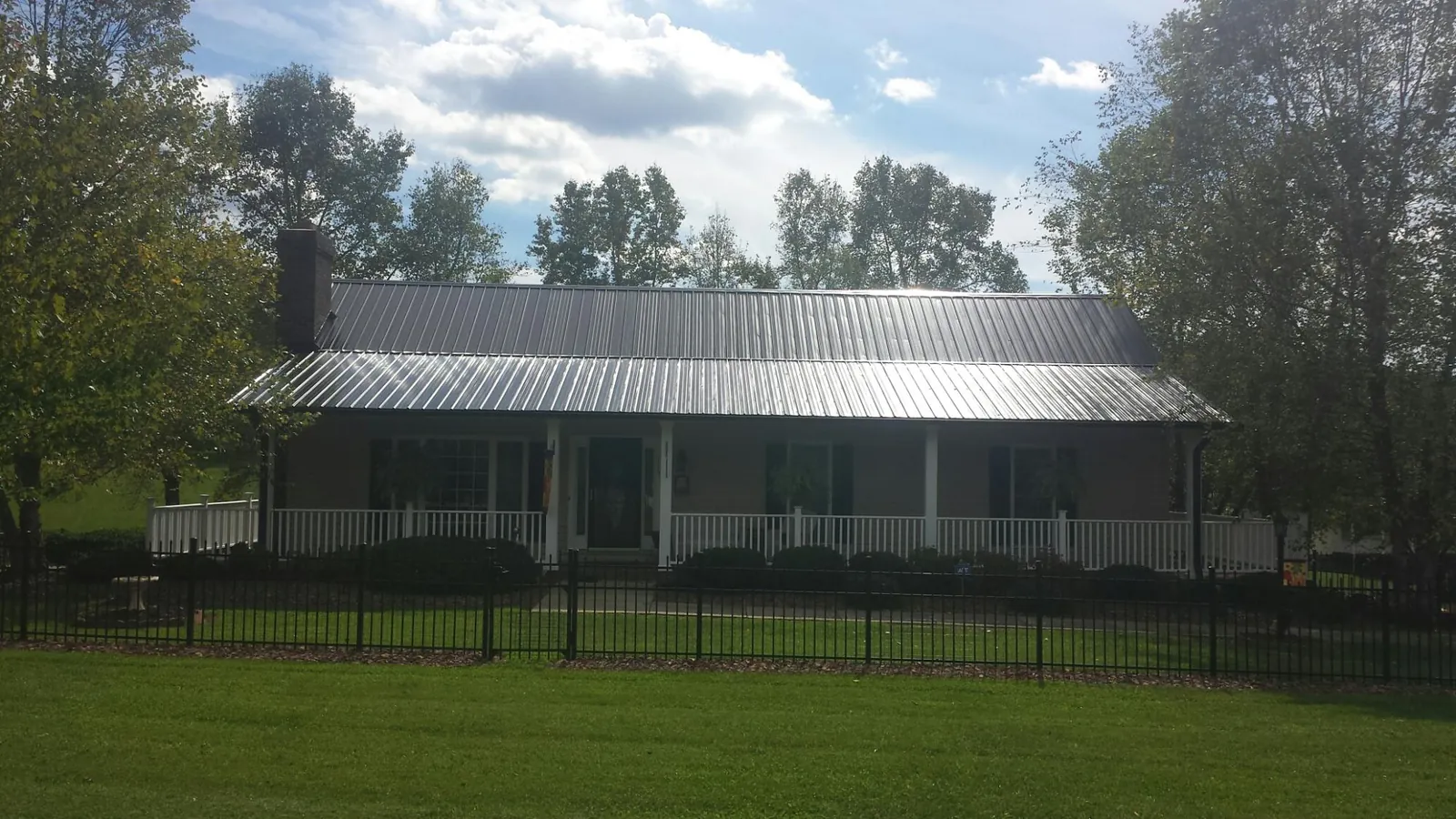 Gray metal roof on a brick ranch with a full width front porch — Gutter Guard Installation work by our crew in Laketon