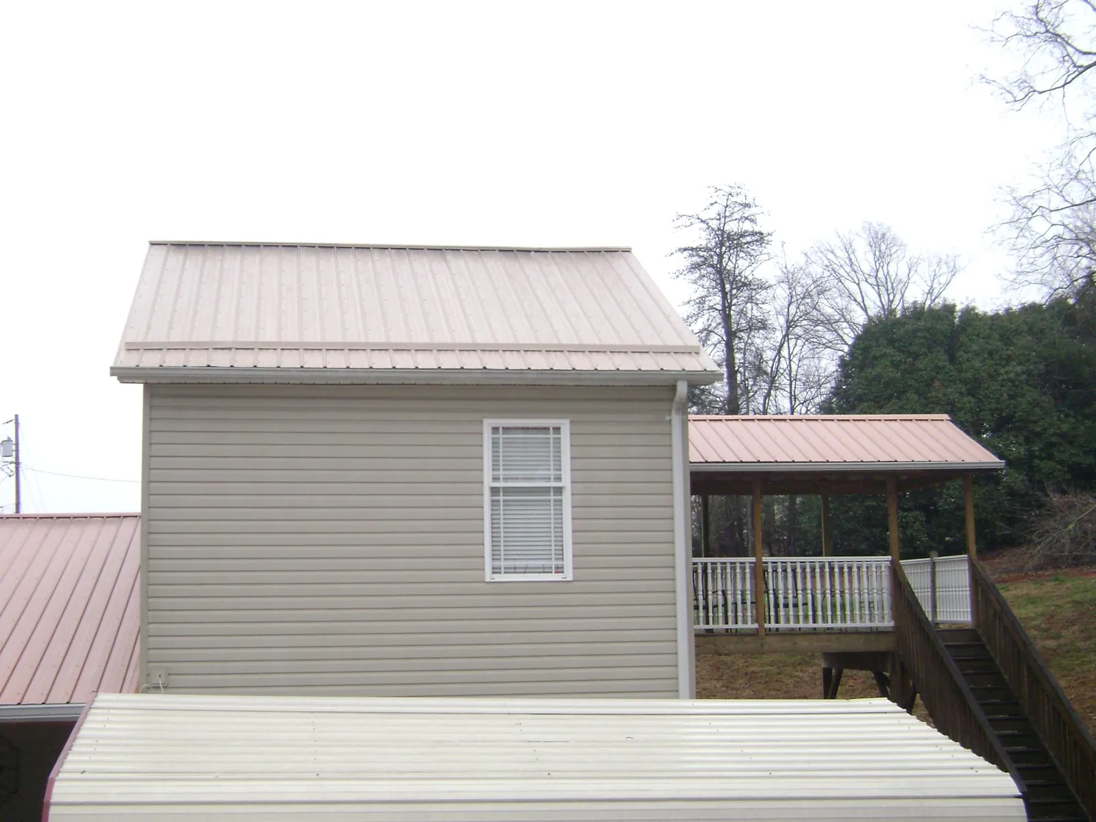 Tan metal roofs on a two story addition and attached porch, from a Roof Replacement job in Laketon