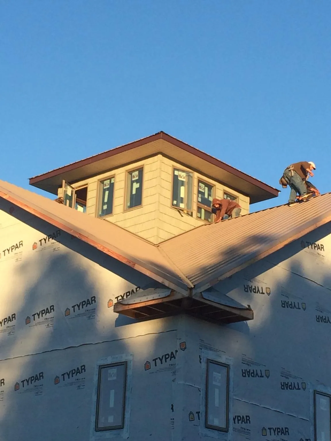 Roofers working around a rooftop cupola on a new metal roof at sunset — Roof Waterproofing in Laketon by Roofing Brothers